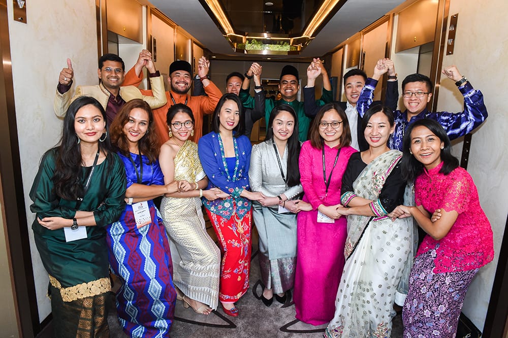 Group of people holding hands, some with arms raised, in a hallway.